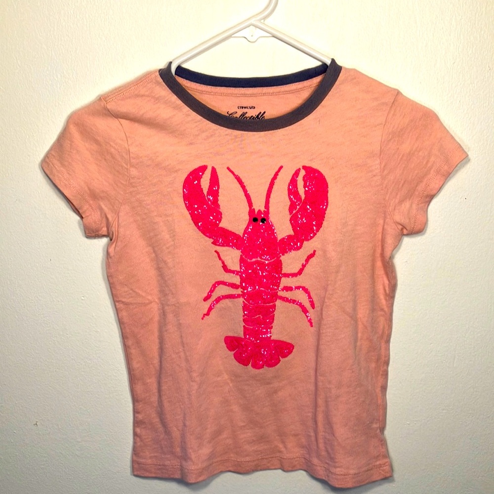 A youth size t-shirt, pink with sequins in the shape of a lobster.